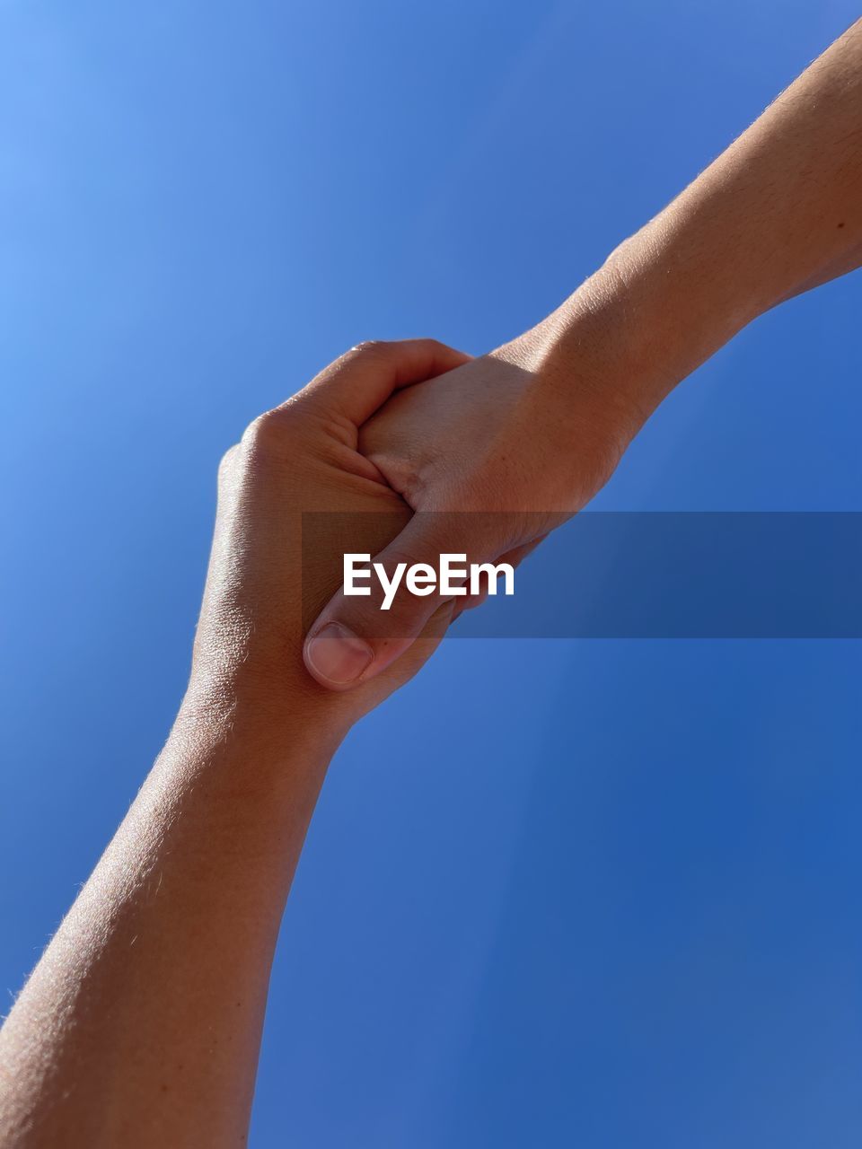 Close up of holding hands against blue background