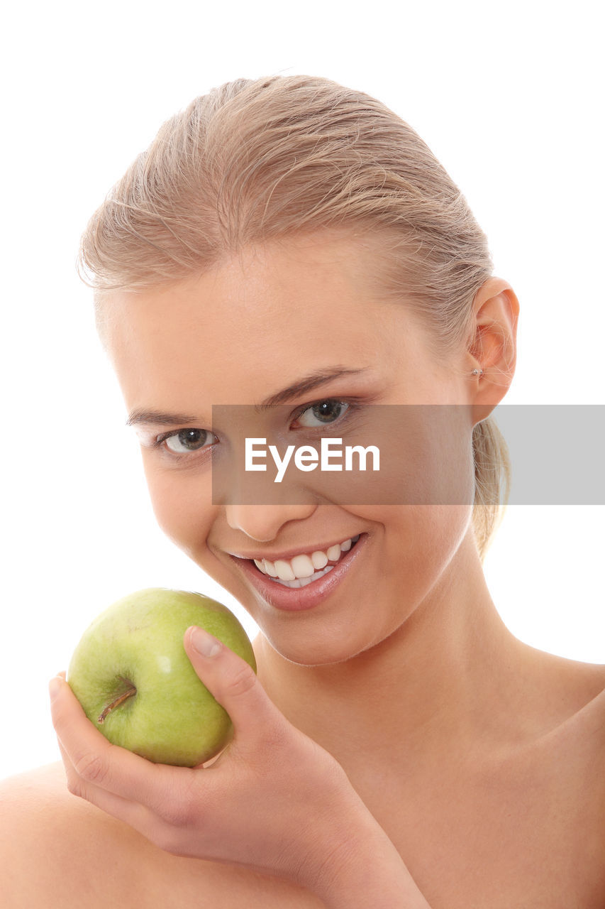 Close-up of woman holding granny smith apple against white background