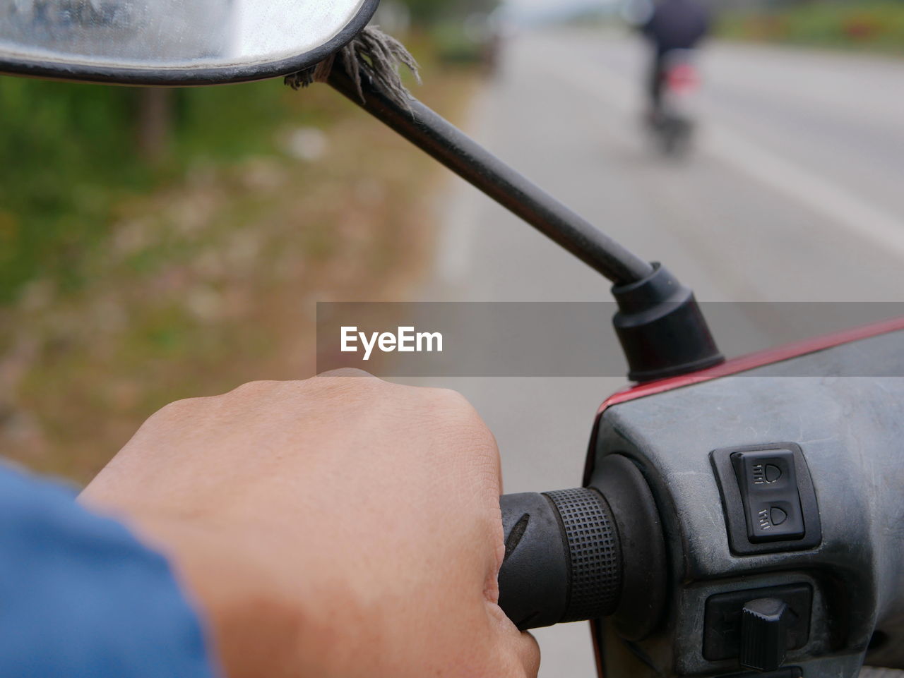 Cropped hand of man motor scooter on road