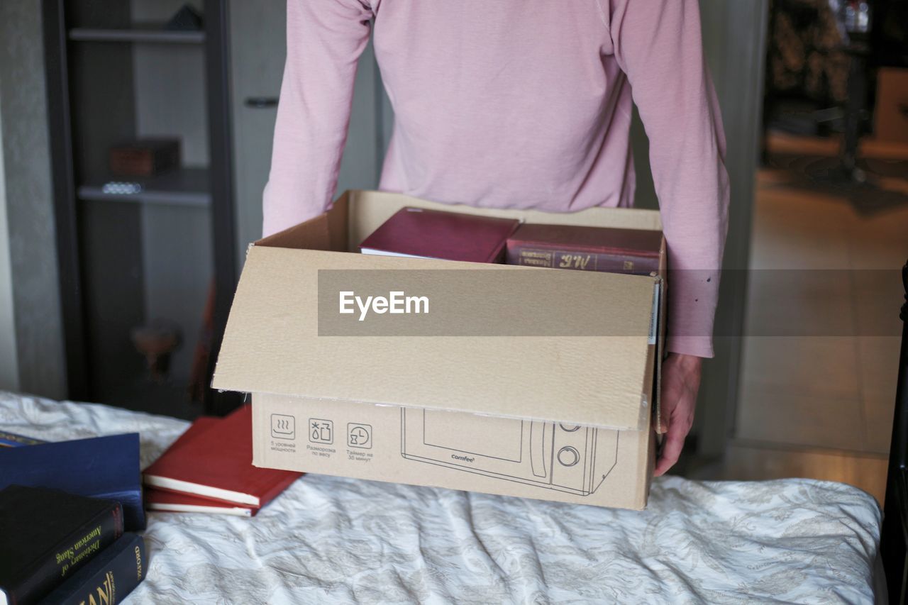 MIDSECTION OF MAN HOLDING BOOK IN BOX