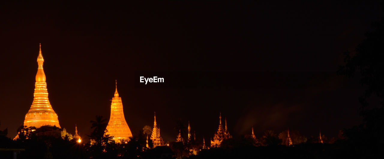 PANORAMIC VIEW OF ILLUMINATED TEMPLE BUILDING AGAINST SKY