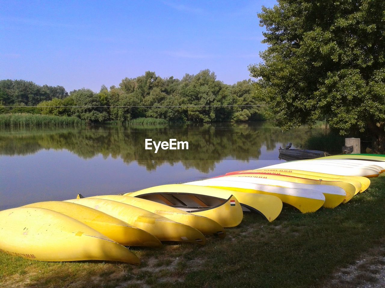 BOATS MOORED IN LAKE AGAINST SKY