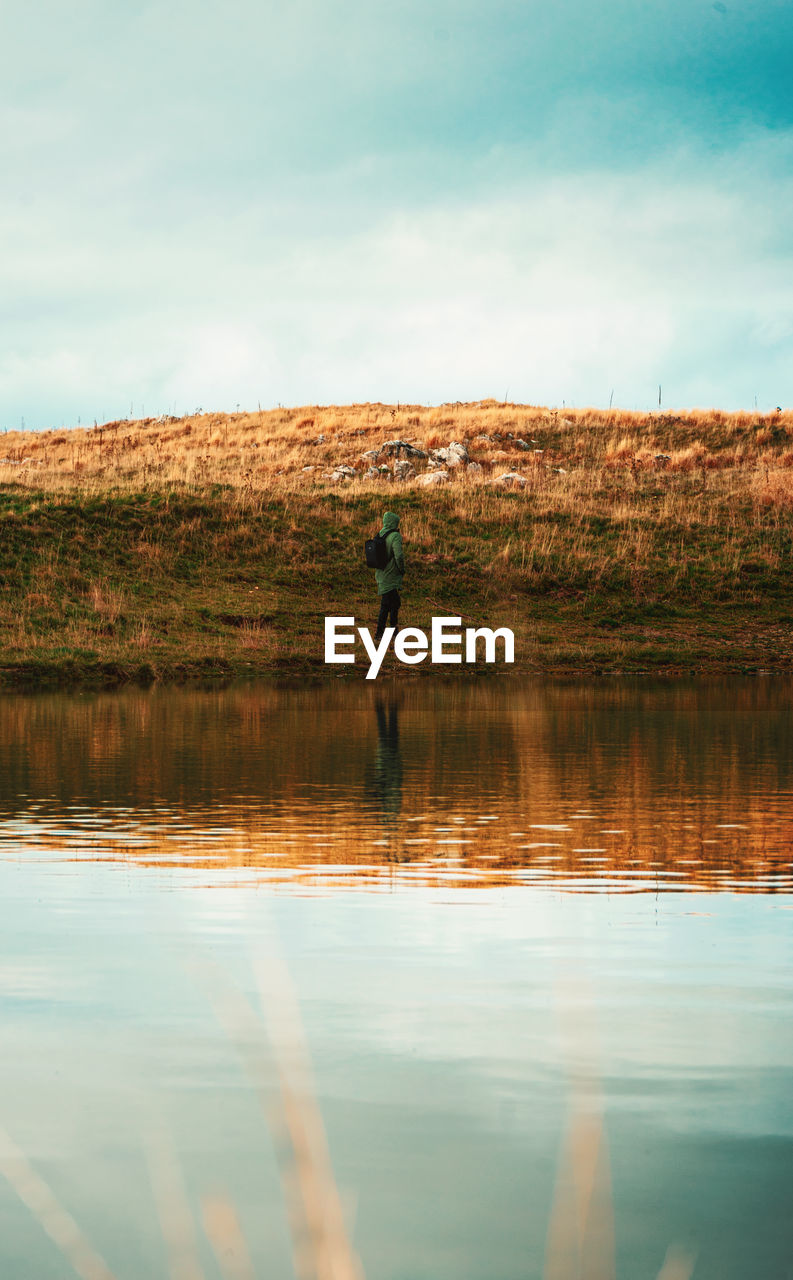 Reflection of man in lake against sky