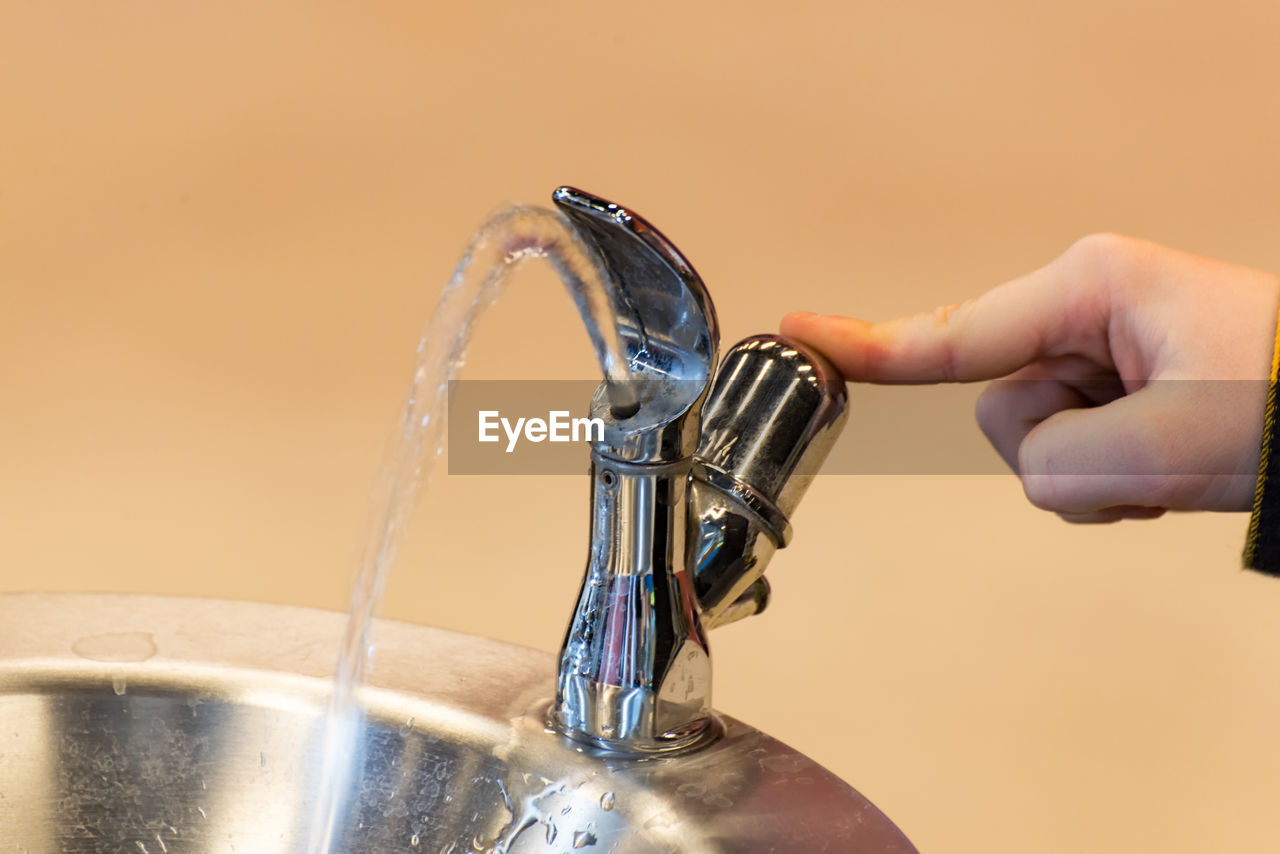 Cropped hand of child pressing tap in bathroom