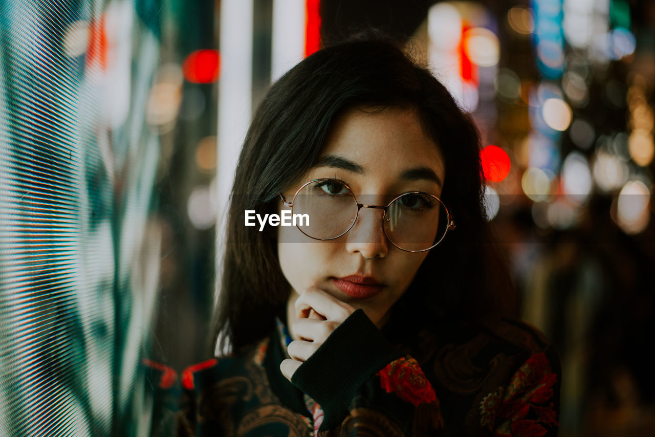 CLOSE-UP PORTRAIT OF A YOUNG WOMAN WITH EYEGLASSES OUTDOORS