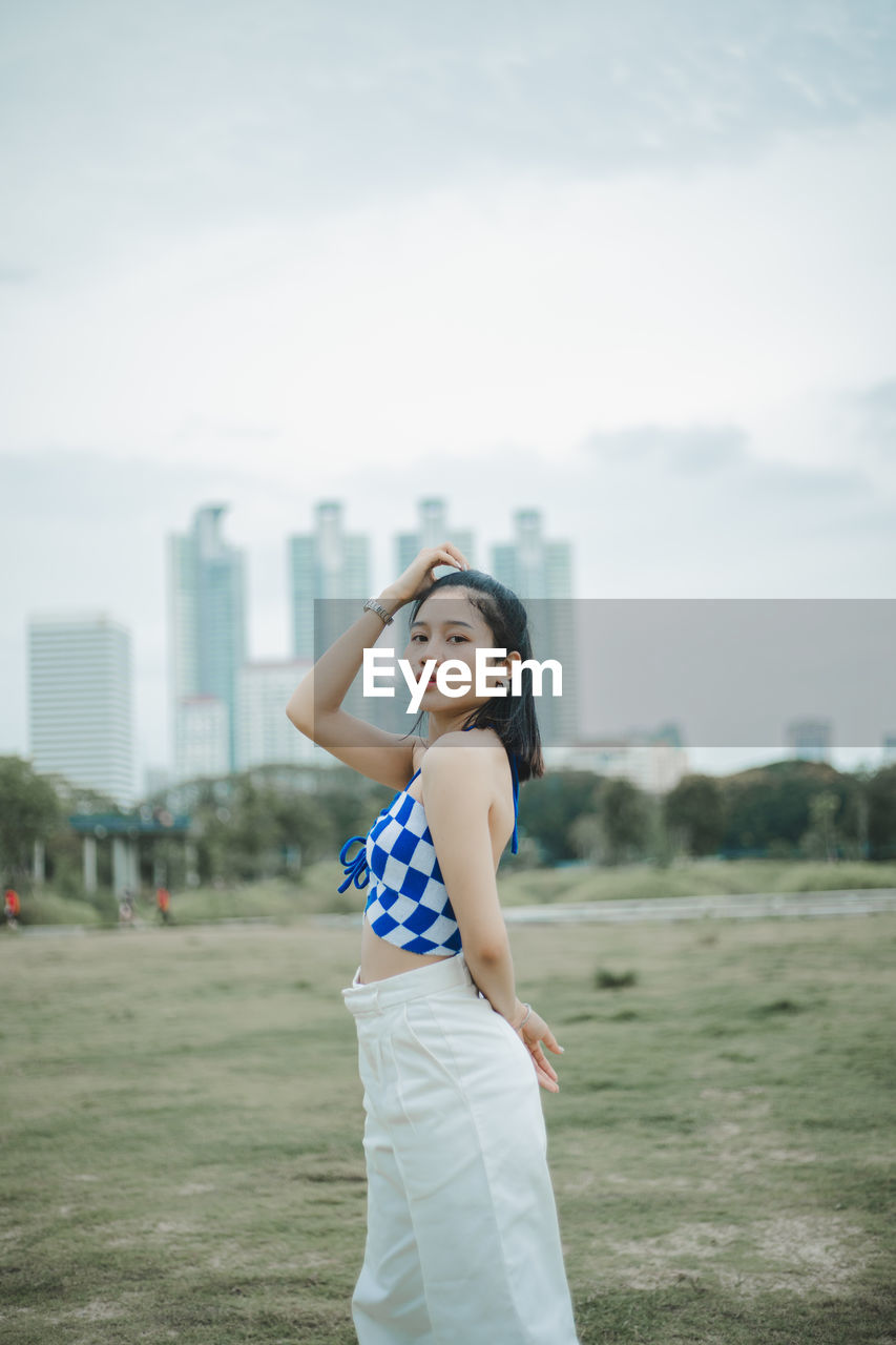 Young woman standing against sky