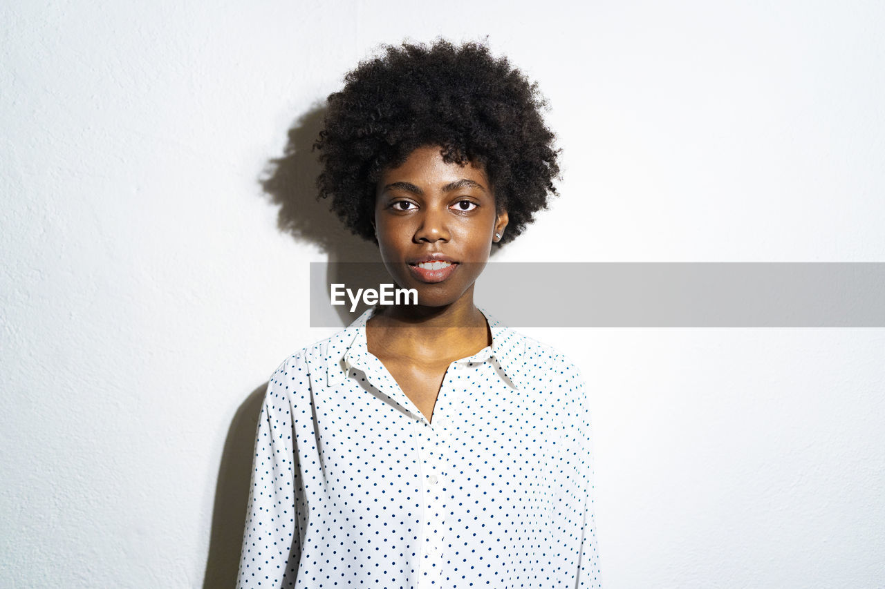 Curly hair woman staring while standing against white background