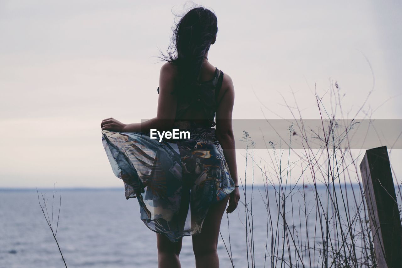 Rear view of young woman looking at sea