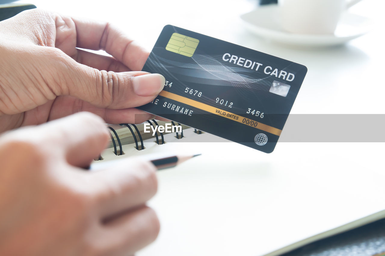 Close-up of hand holding credit card on table