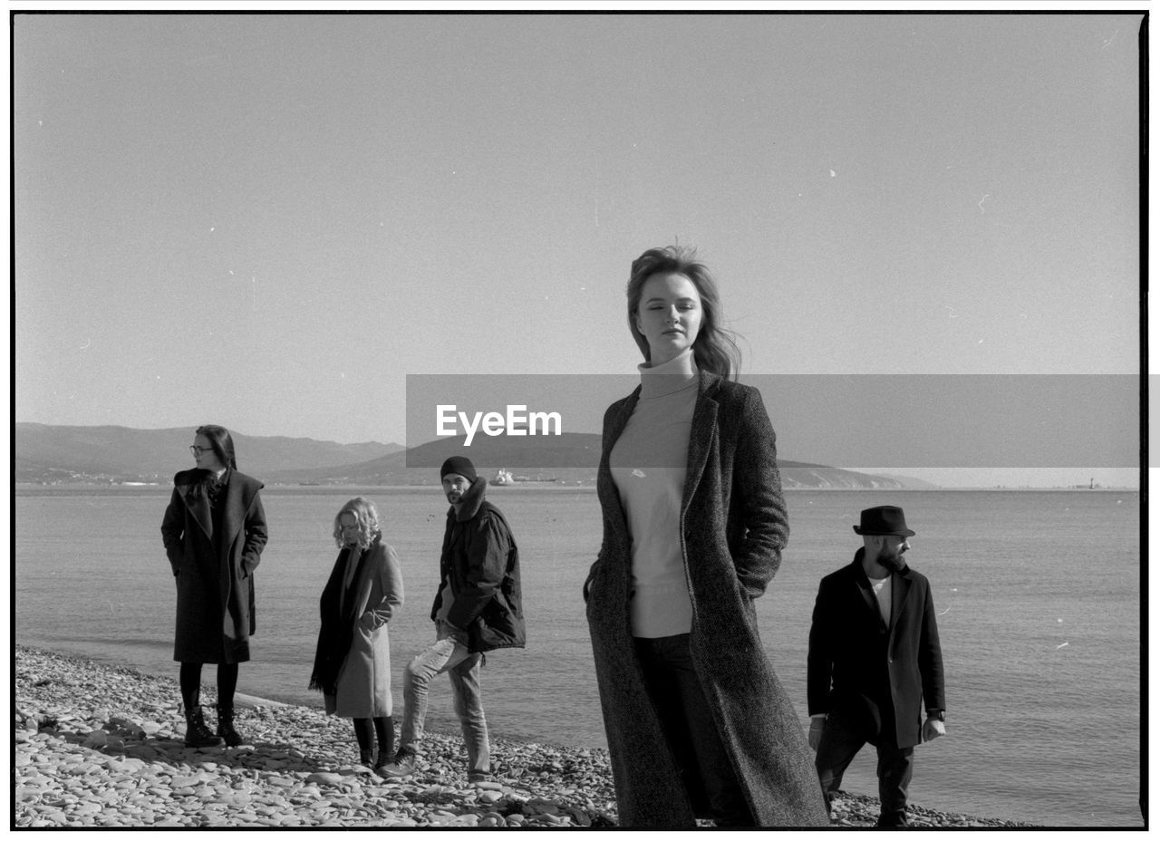 People standing at beach against clear sky