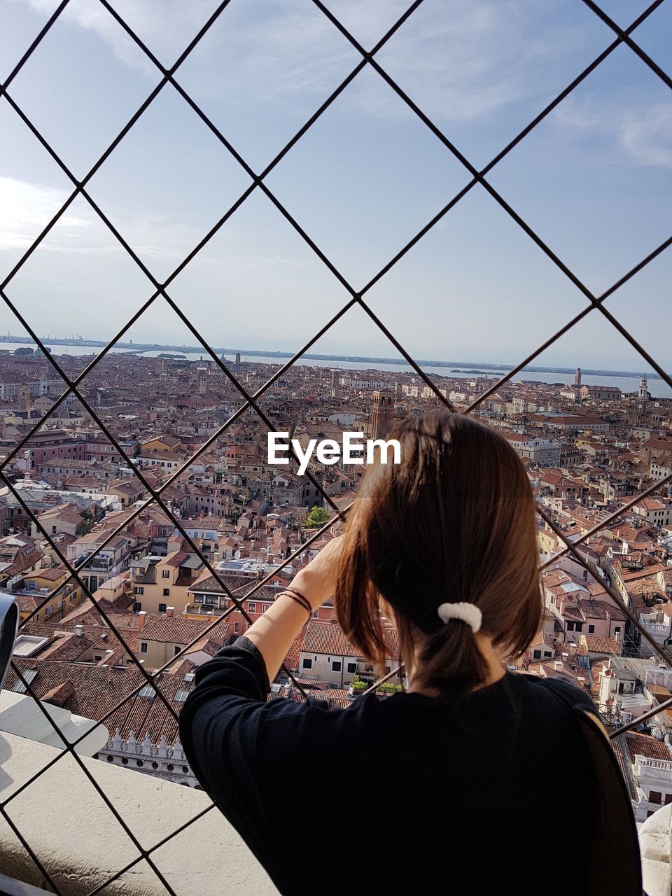 REAR VIEW OF WOMAN ON CITYSCAPE AGAINST SKY