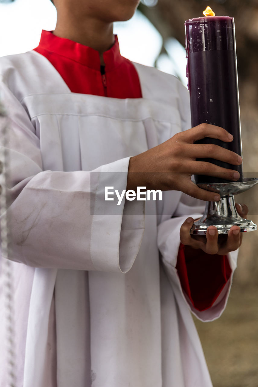 Seminarian carries a seven-day candle on the day of the dead holiday at the campo santo cemetery