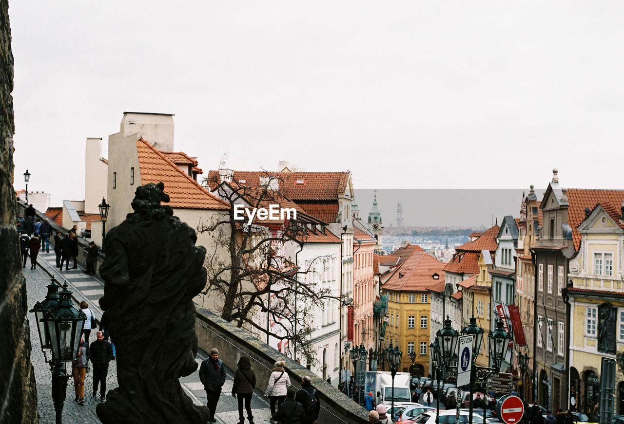 People on street amidst buildings in city against sky