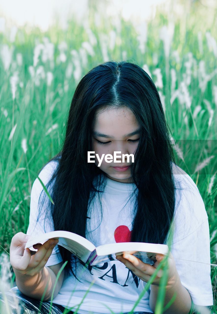 Girl reading book on lawn