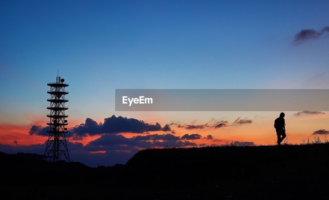 Silhouette man walking on field against sky during sunset