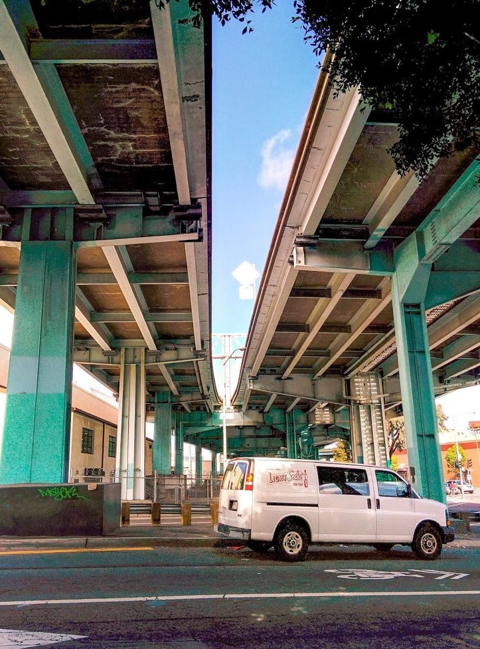 VIEW OF VEHICLES ON ROAD ALONG BUILDINGS