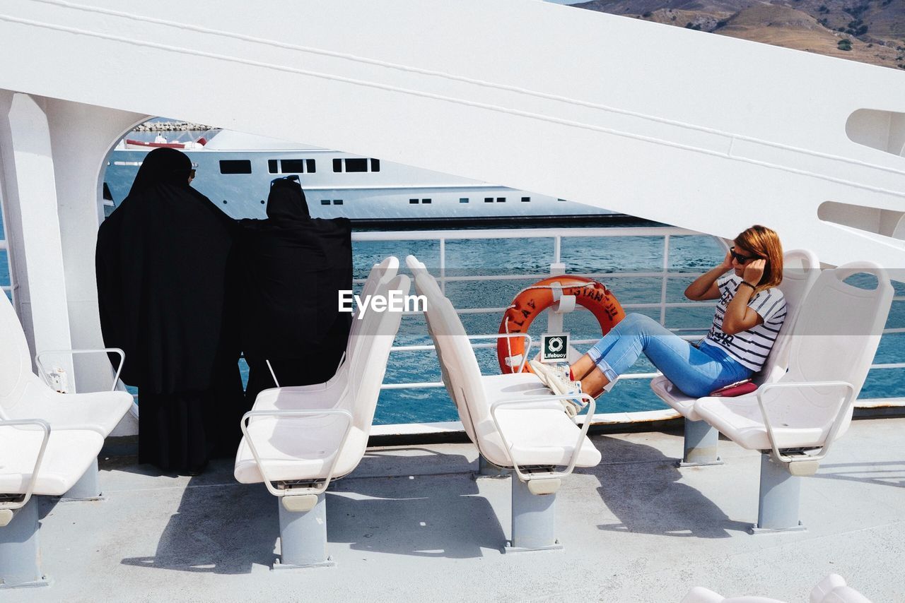 REAR VIEW OF MAN AND WOMAN SITTING IN BOAT