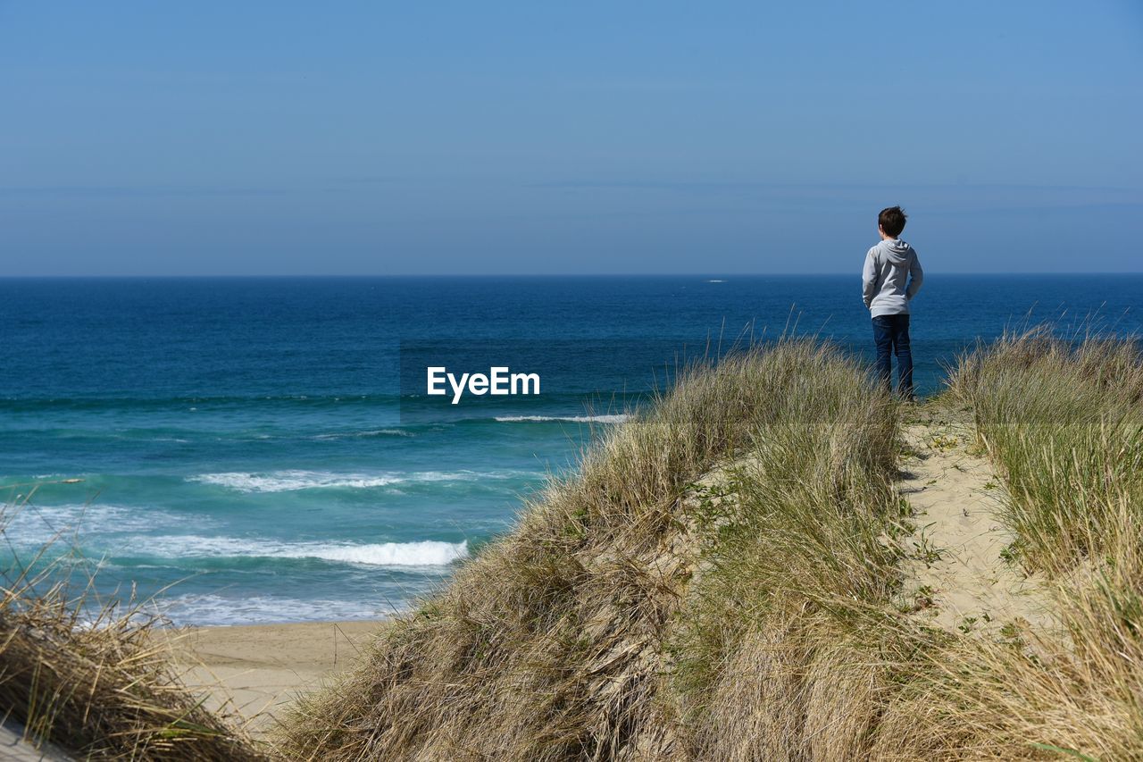 Boy looking at sea against sky