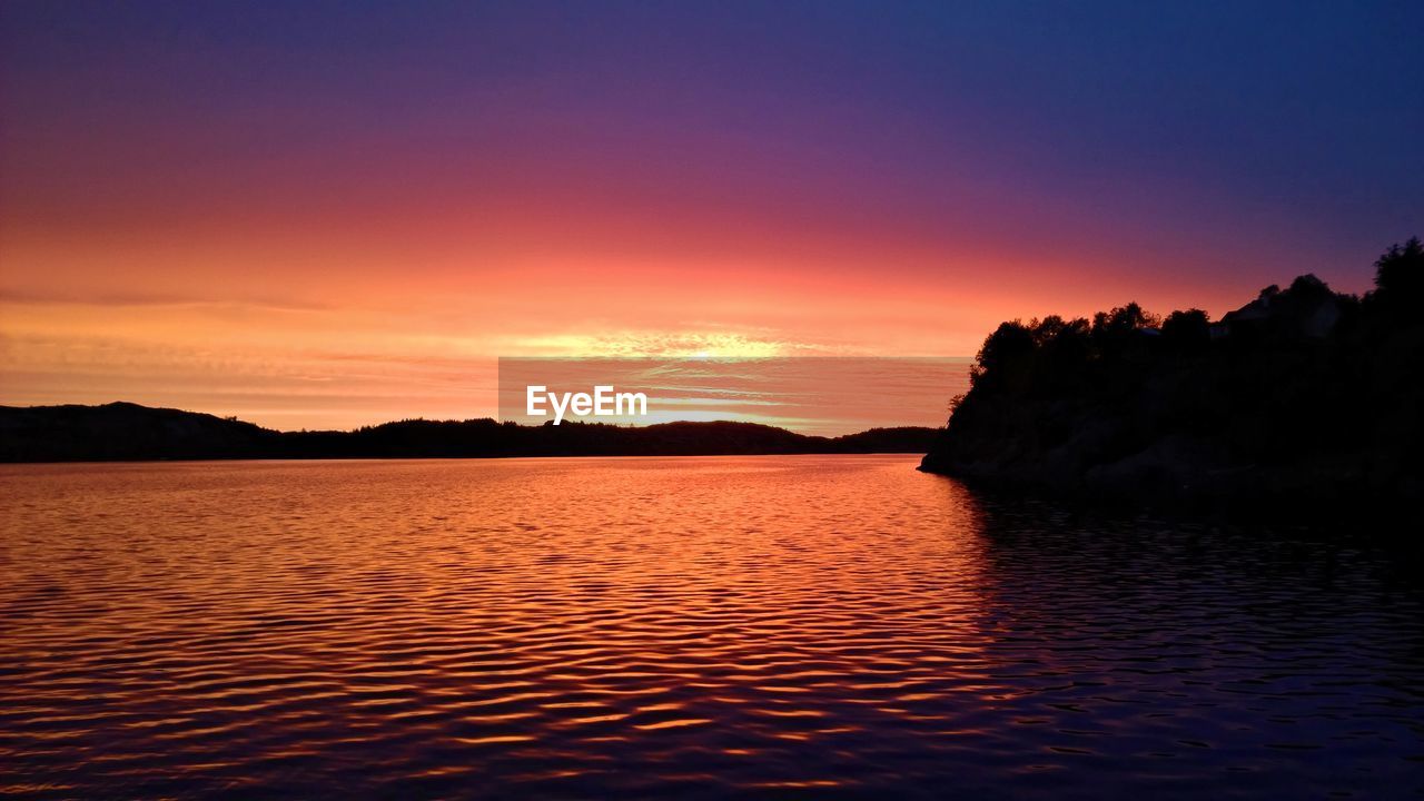 Scenic view of sea against dramatic sky during sunset