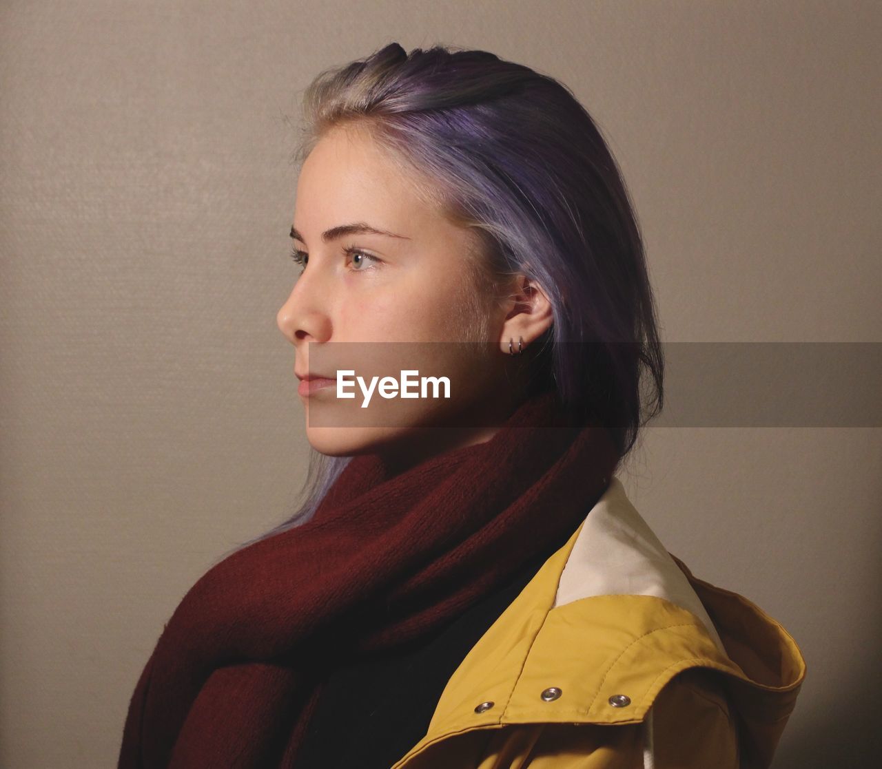 Young woman looking away against brown background