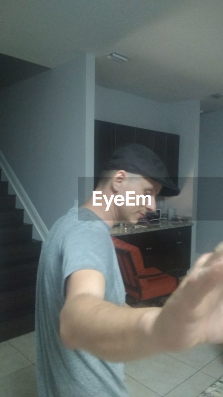 SIDE VIEW OF YOUNG MAN USING LAPTOP AT HOME