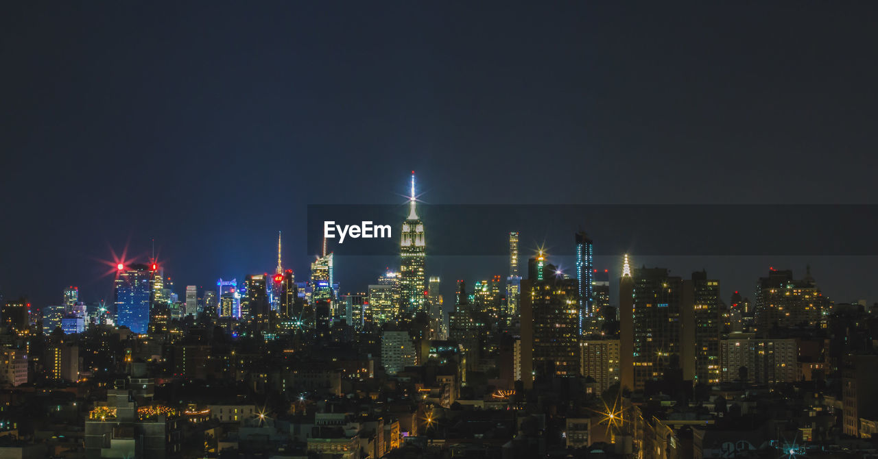 ILLUMINATED MODERN BUILDINGS IN CITY AT NIGHT