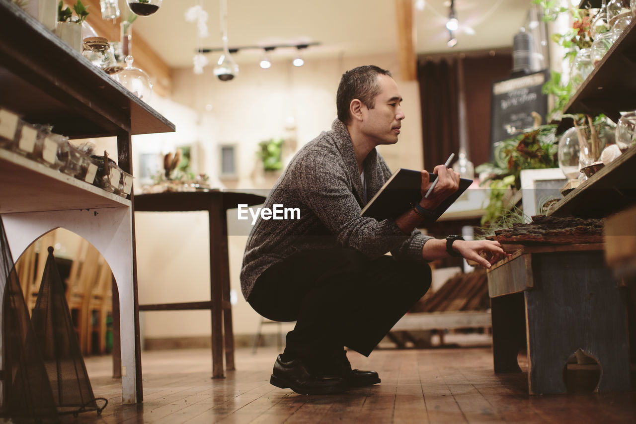 Worker examining plants in garden center