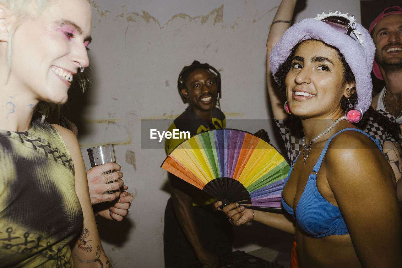 Smiling non--binary person partying with friends at nightclub