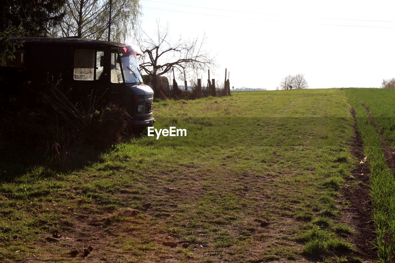 TRACTOR ON FIELD BY TREES AGAINST SKY