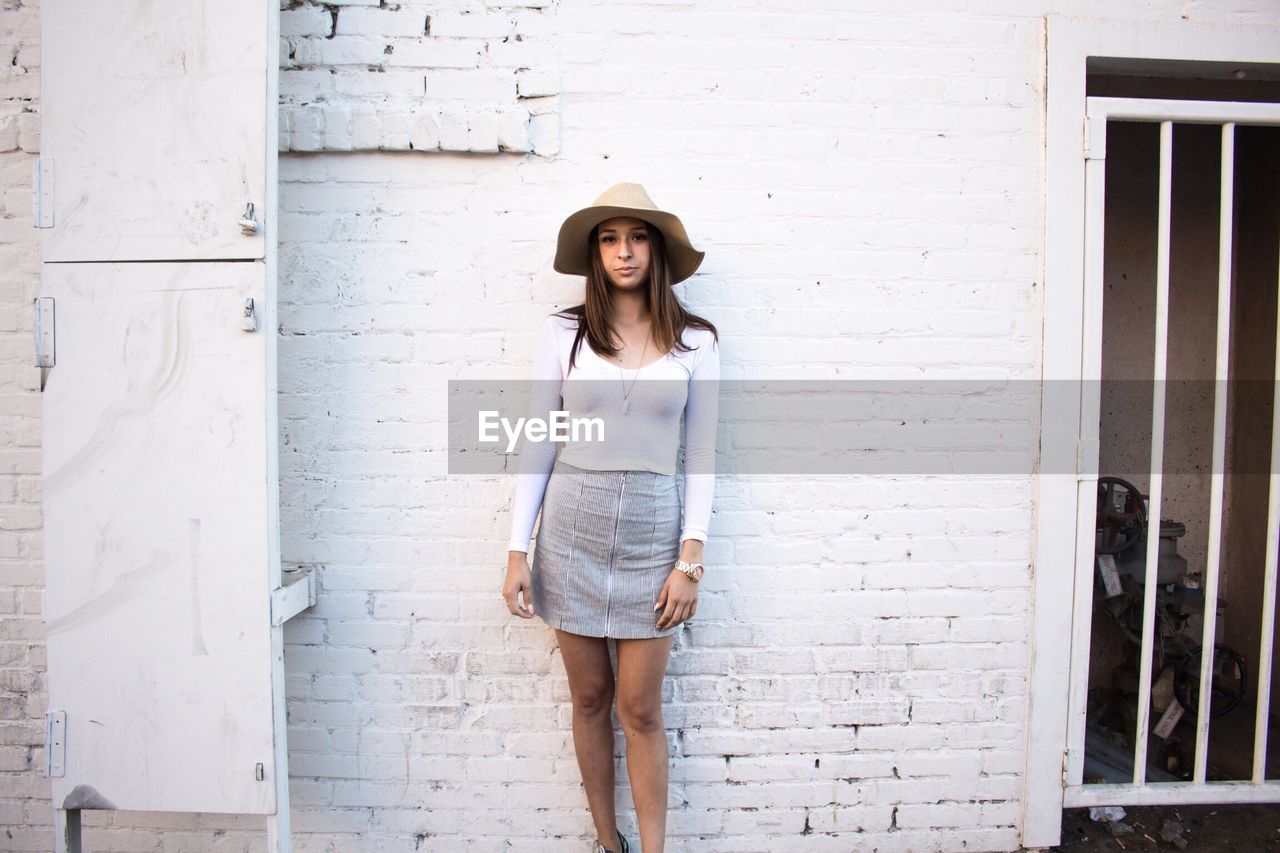 PORTRAIT OF YOUNG WOMAN STANDING ON WALL