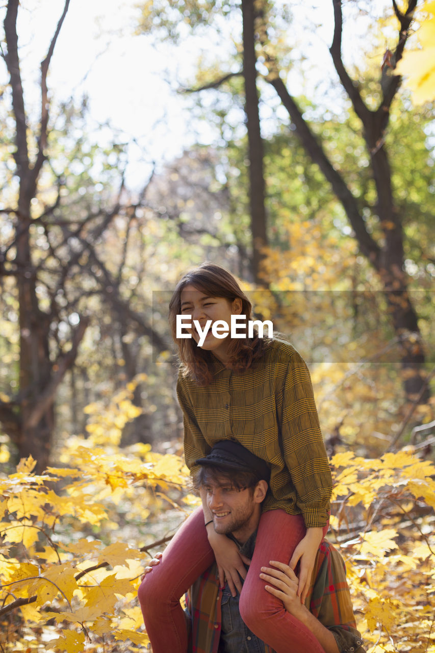 Young woman playfully sitting on her boyfriend's shoulders