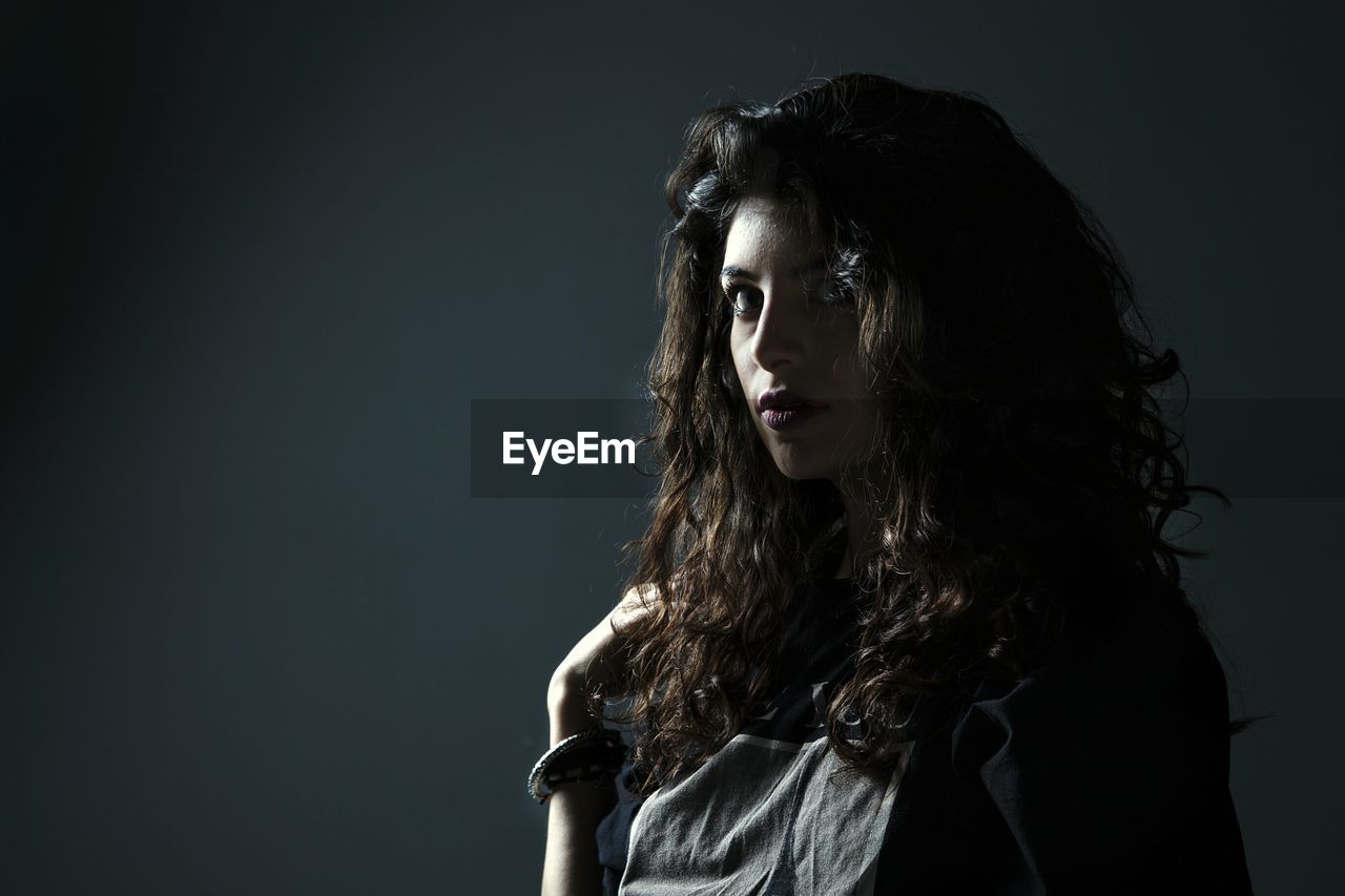 Portrait of young woman against black background