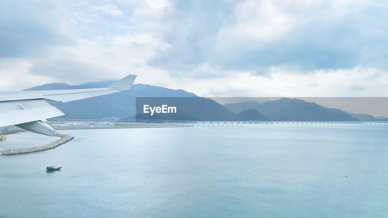 Scenic view of sea by mountains against sky