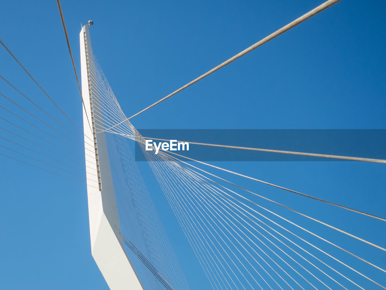 Low angle view of suspension bridge against clear blue sky