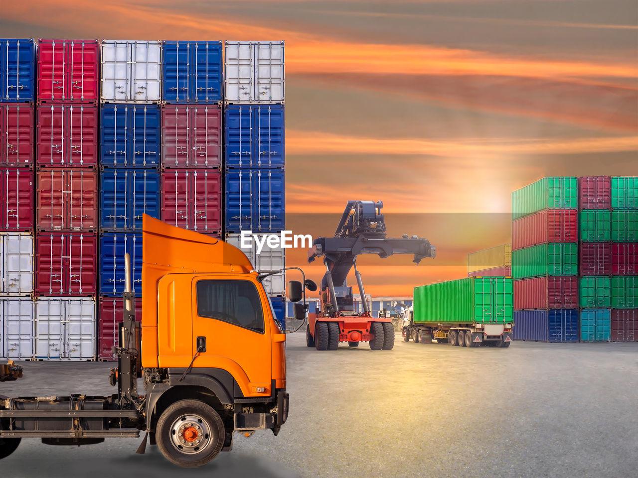 Stack of truck against orange sky during sunset