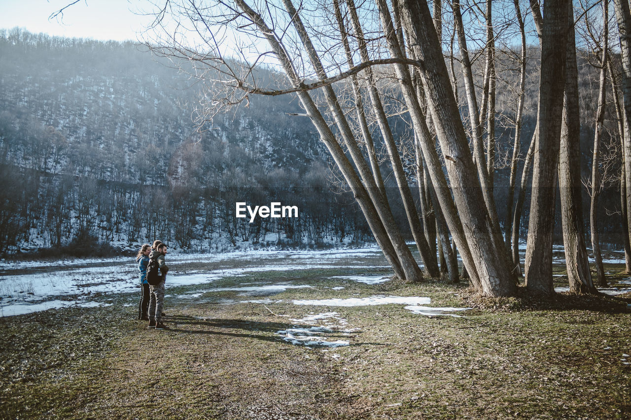 People standing by bare trees at park