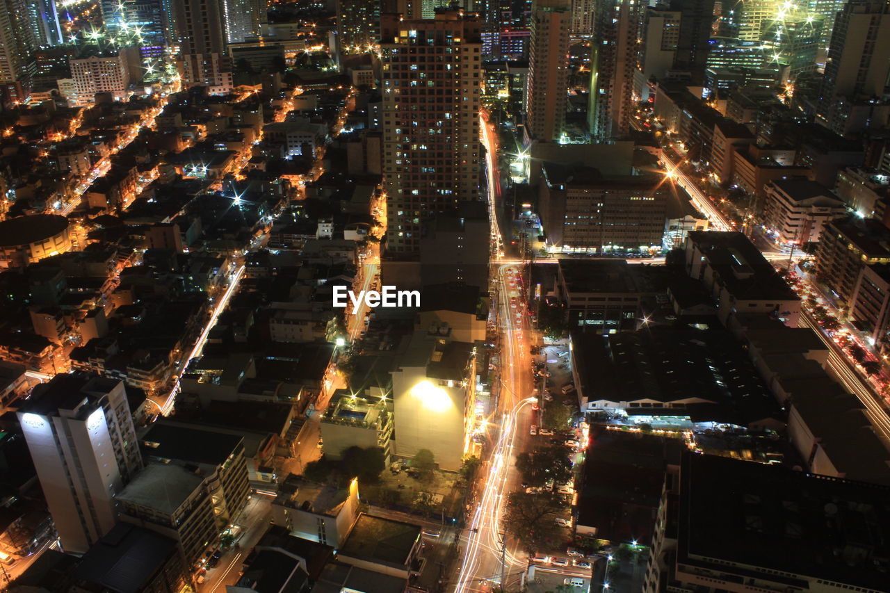 HIGH ANGLE VIEW OF ILLUMINATED STREET AMIDST BUILDINGS IN CITY