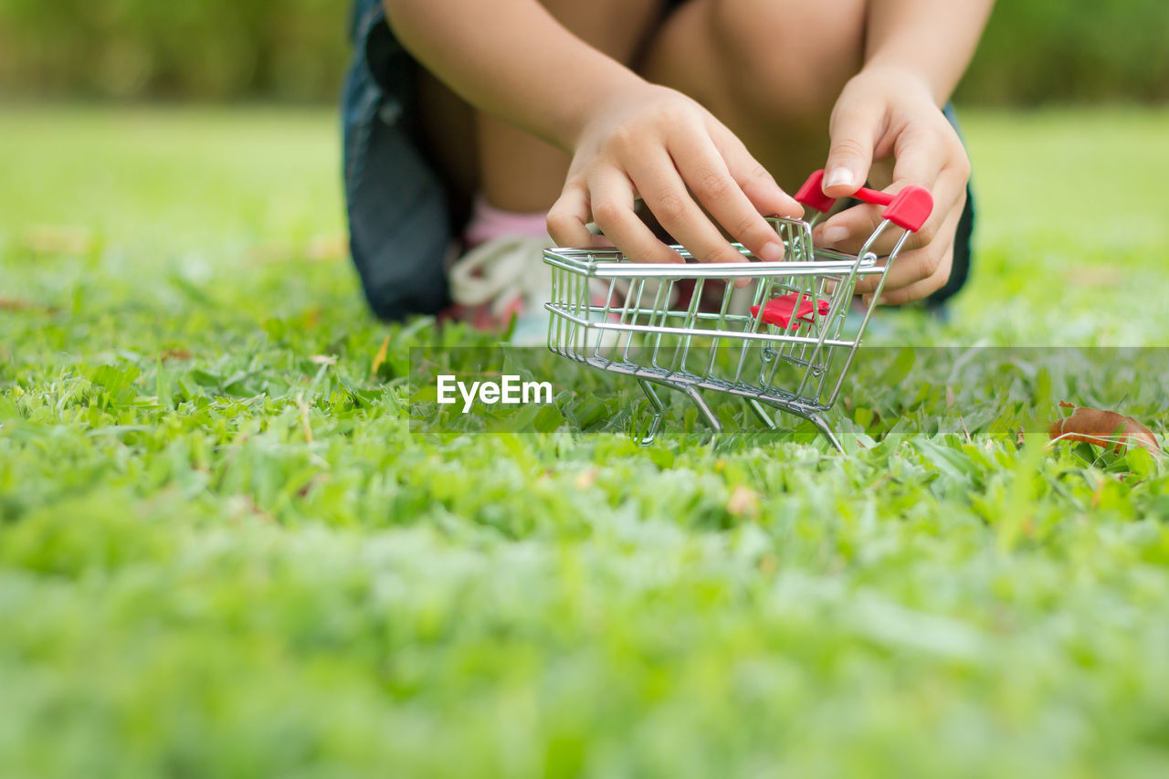 Low section of girl playing with shopping cart on field