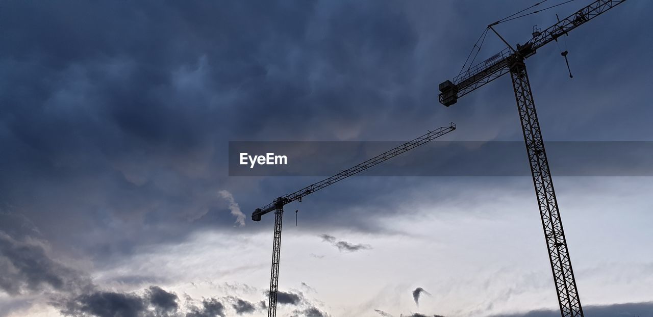 Low angle view of cranes against sky