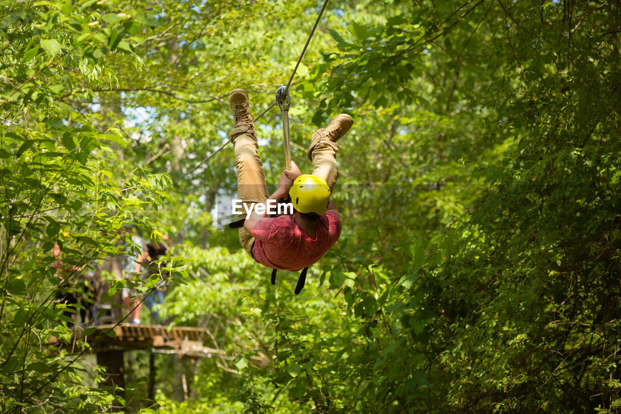 Low angle view of man zip lining in forest