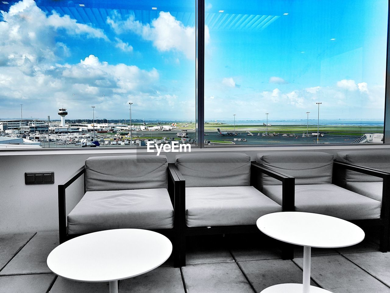 Empty chairs and table at airport against blue sky