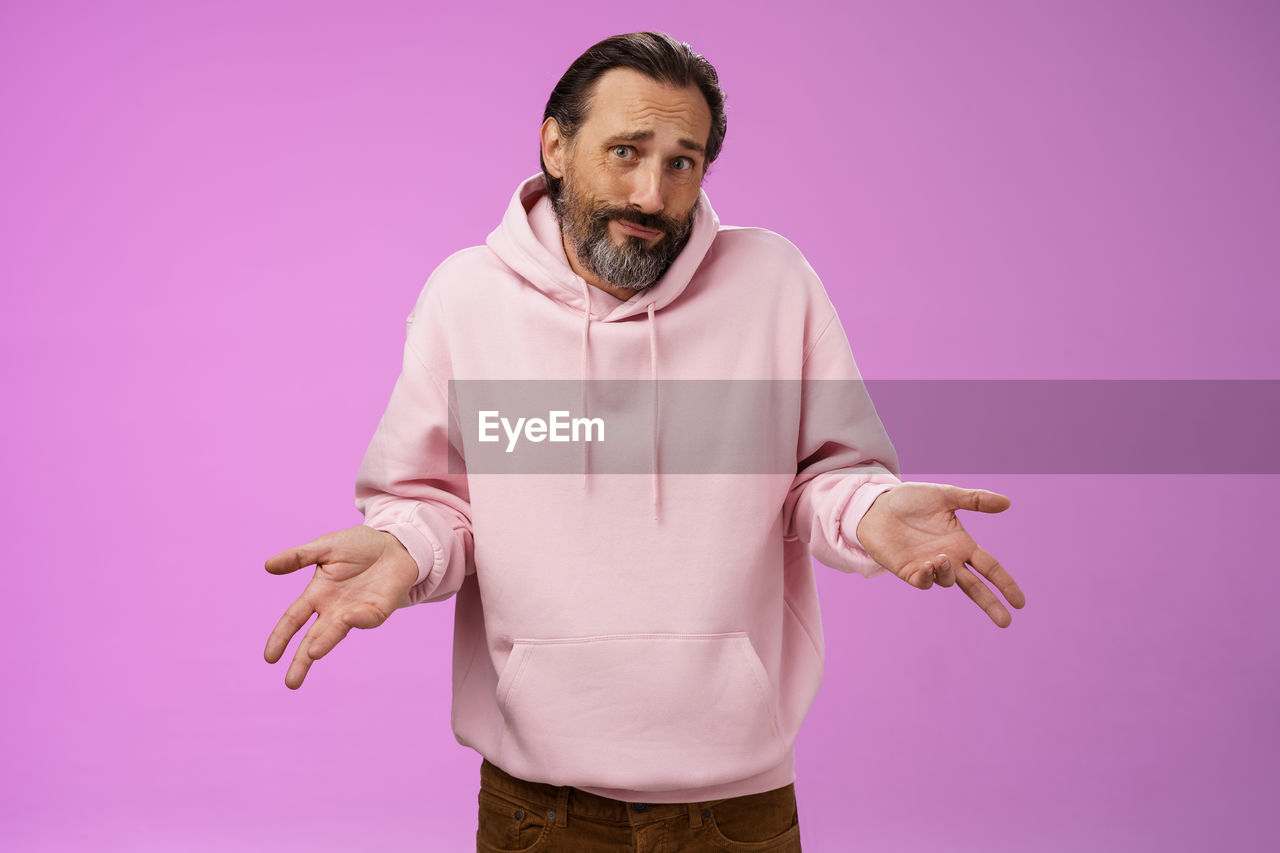 PORTRAIT OF MAN STANDING ON PINK BACKGROUND