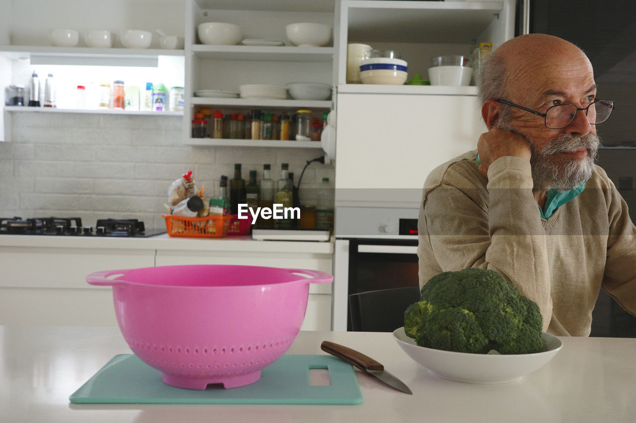 side view of senior man preparing food on table