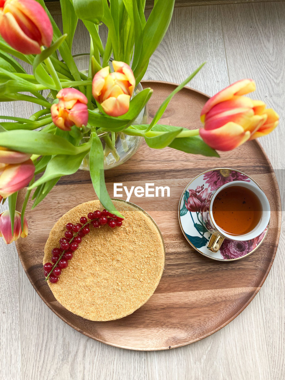 High angle view of tulips, cake and a cup of tea on a wooden tray