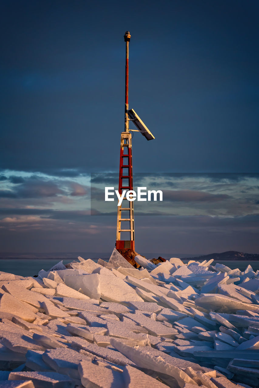 Windmill on snow covered landscape against blue sky