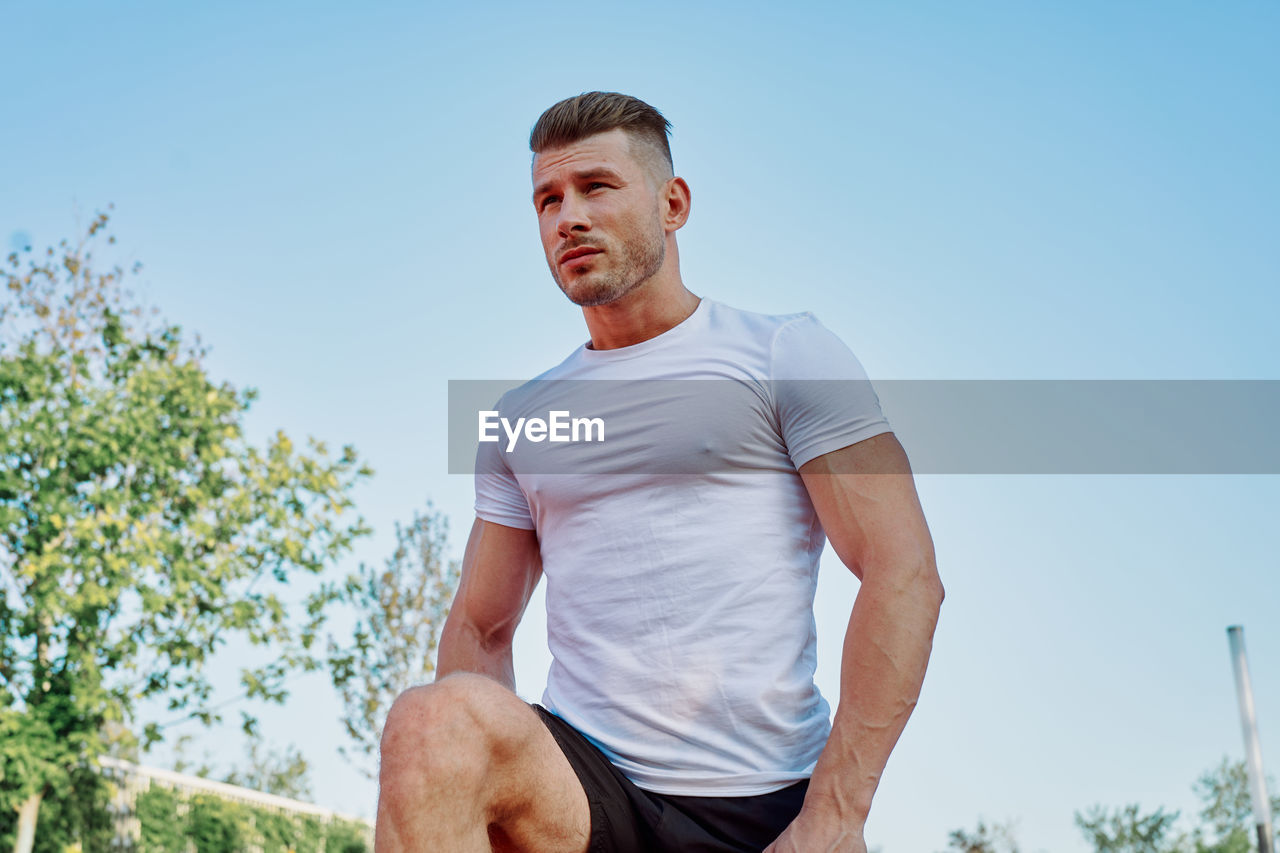 low angle view of young man exercising against sky