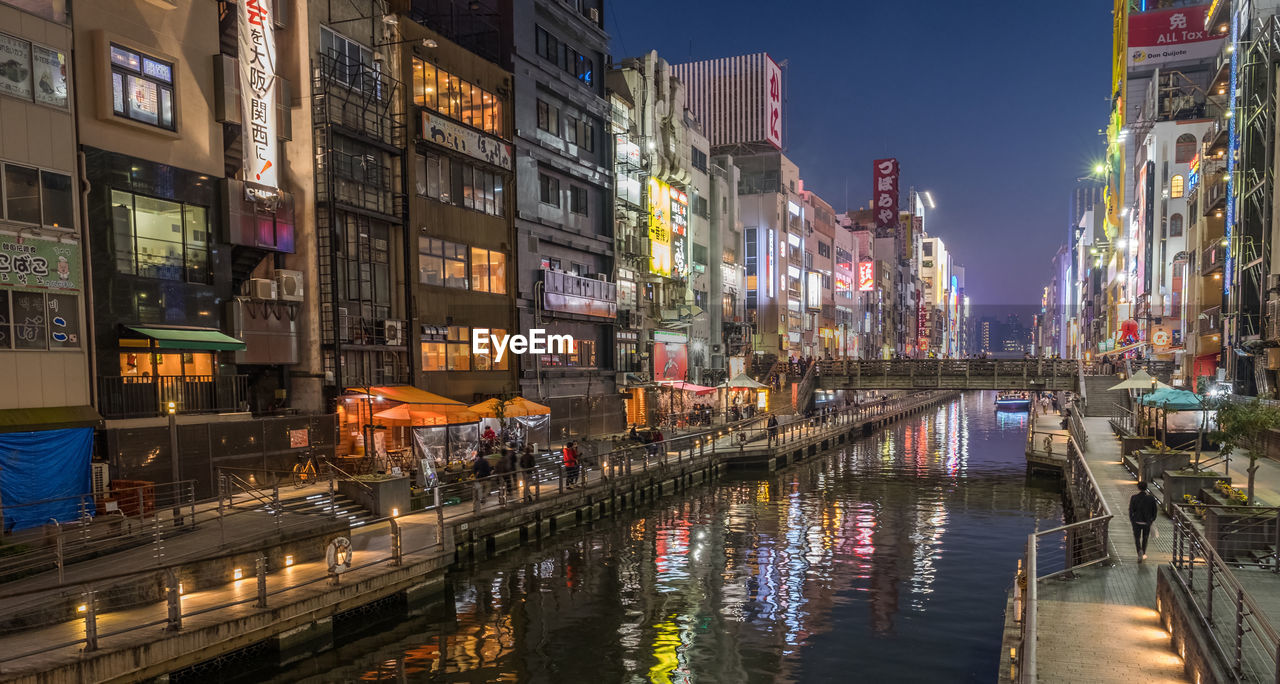 Canal amidst illuminated buildings in city at night