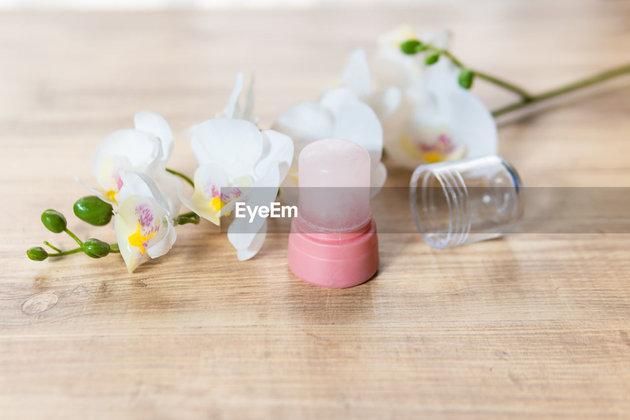 CLOSE-UP OF WHITE FLOWERS IN GLASS ON TABLE