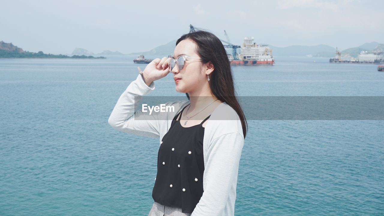 Young woman wearing sunglasses against sea 
