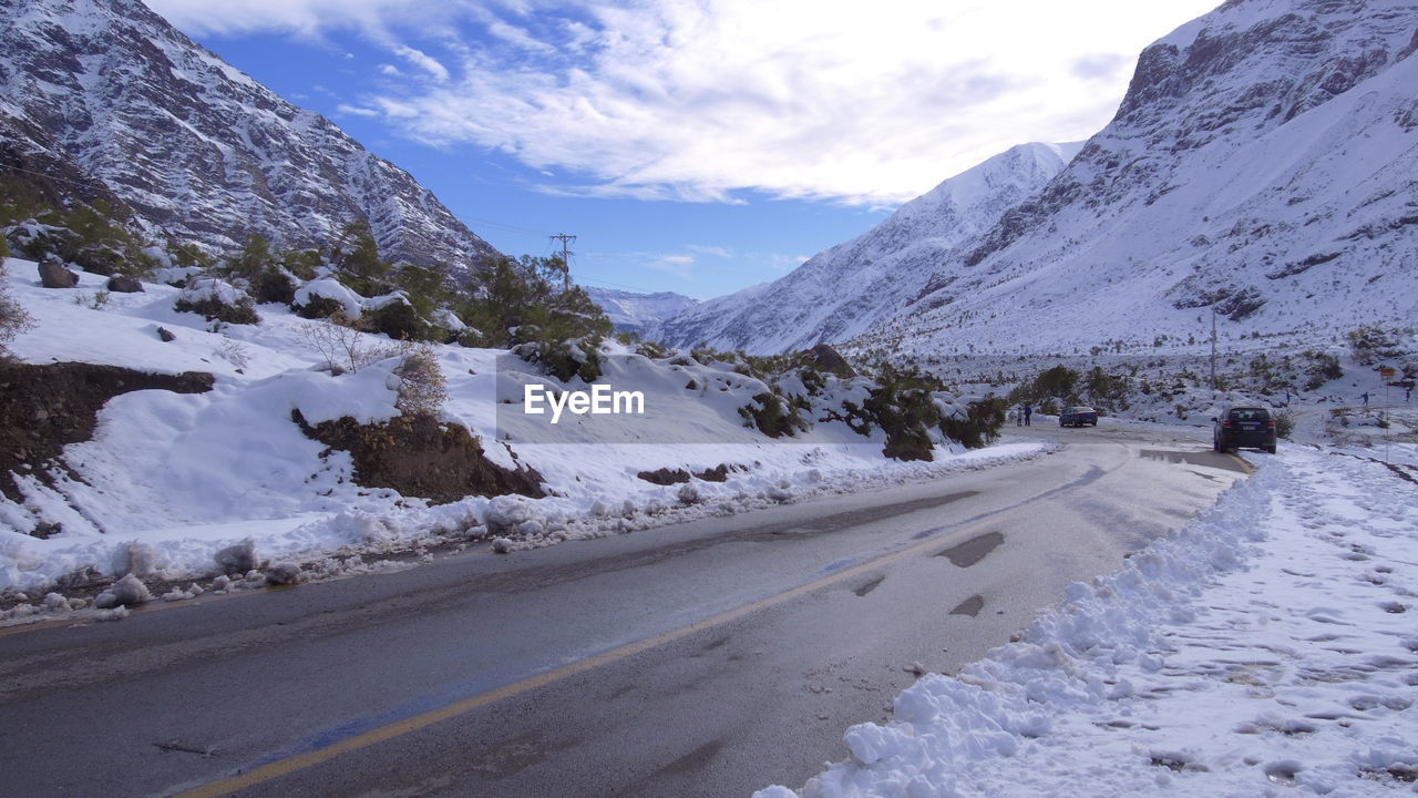 Road by snow covered mountains against sky